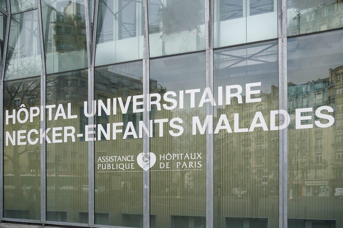 A building facade with the text "HÔPITAL UNIVERSITAIRE NECKER-ENFANTS MALADES" and "ASSISTANCE PUBLIQUE HÔPITAUX DE PARIS".