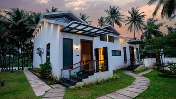 Una casa moderna de dos pisos con techo plano, ventanas amplias y una escalera que conduce a la entrada.