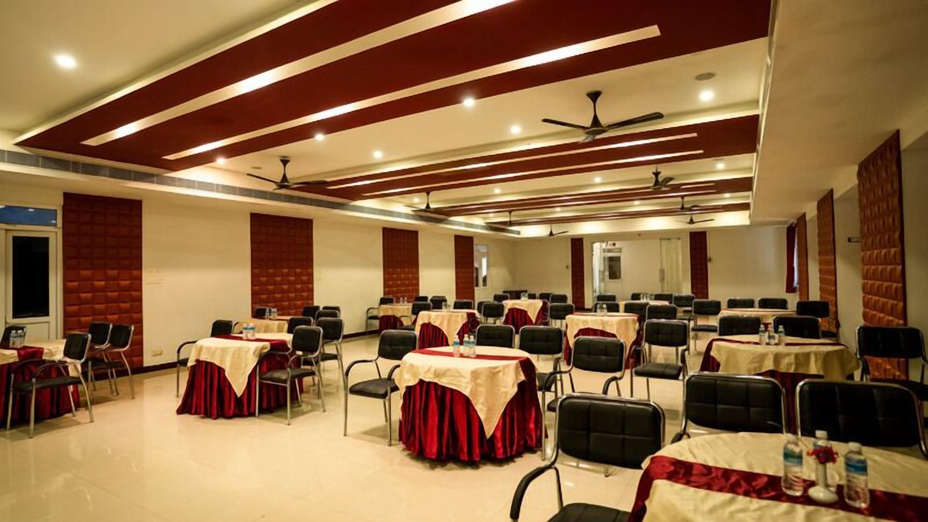 Un salón de conferencias con varias mesas y sillas, ventiladores de techo e iluminación empotrada.