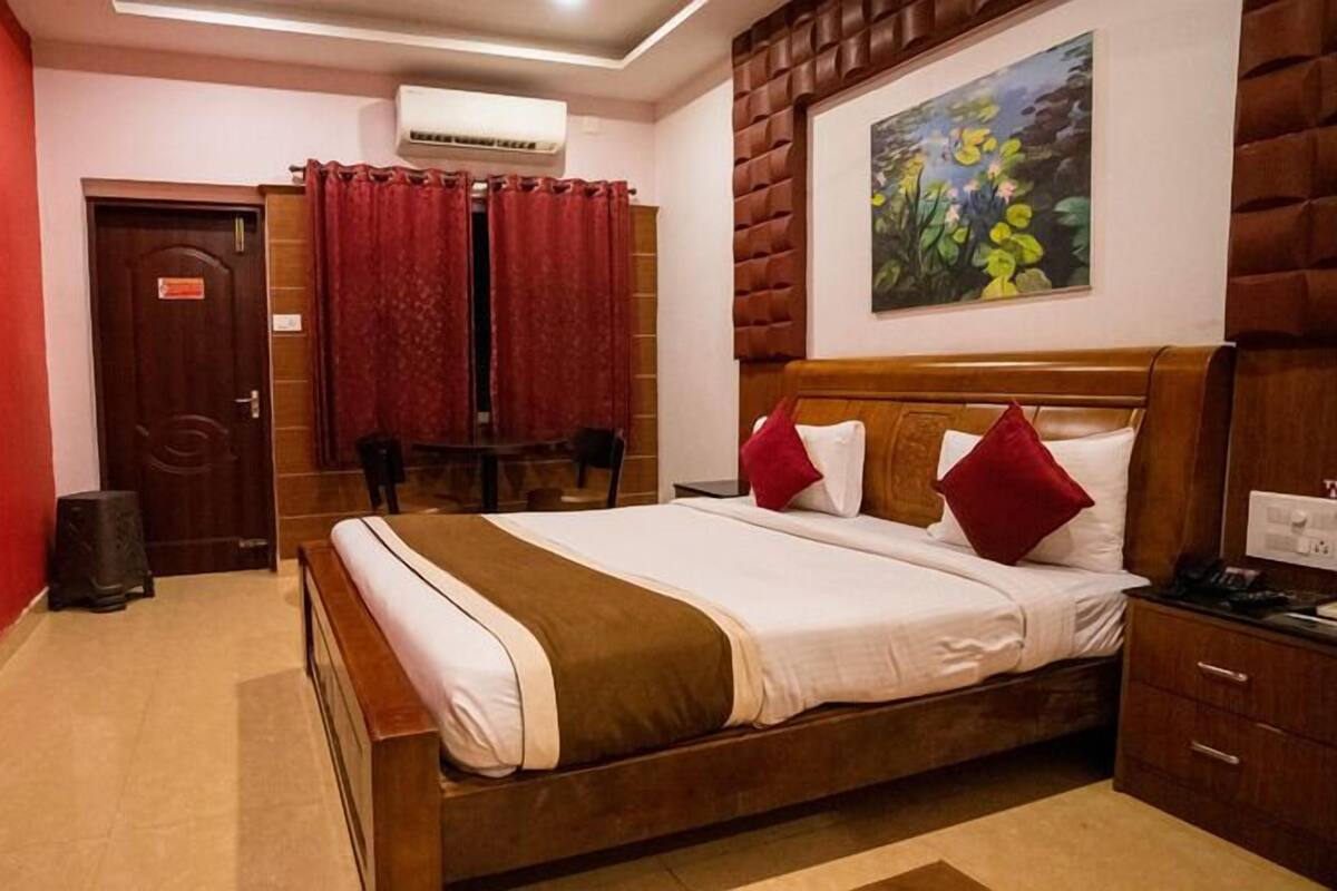 A hotel room with a wooden bed, red curtains, a painting of flowers, and a red wall.