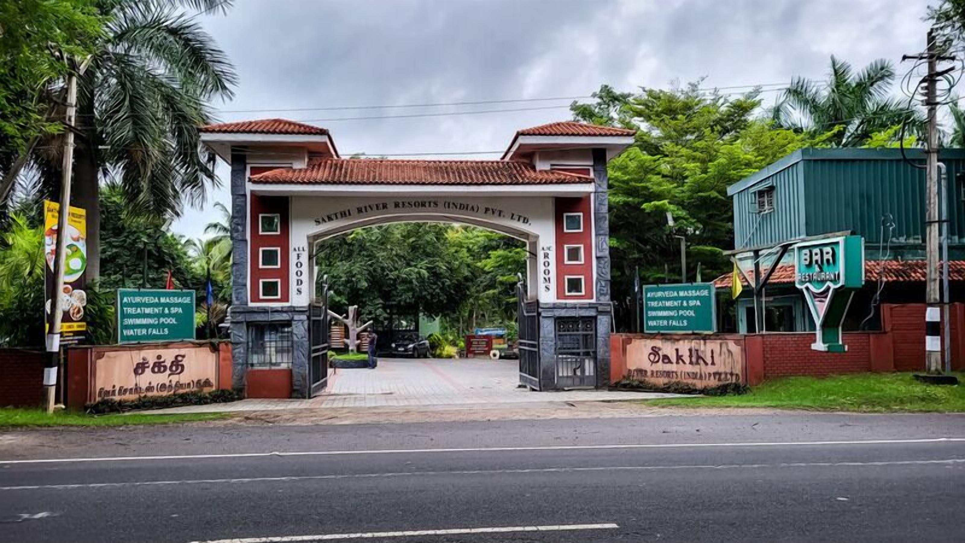 L’entrée du Sakthi River Resorts est signalée par un panneau indiquant les différents services proposés, tels que des massages et des soins ayurvédiques, un spa, une piscine et des cascades.