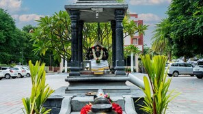 A temple with a central statue, surrounded by greenery and parked cars. - Sakthi River Resorts (Anaimalai)