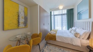 Ein modernes Hotelzimmer mit einem Bett, einem Esstisch mit Stühlen und einem großen, abstrakten Gemälde an der Wand.