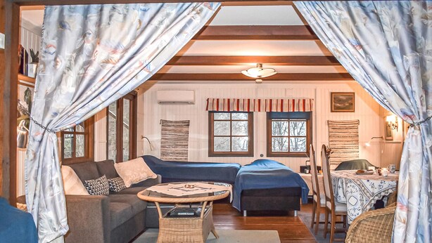 A cozy room with a sofa, two single beds, a small table, and a chair.