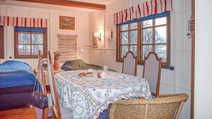 A cozy room with a wooden table set for dining, a bed with a blue cover, and a window with striped curtains.