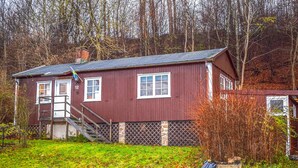 A red wooden house with a small porch and a flag.