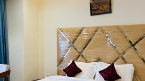 Una cama bien hecha con cabecera de madera, ropa de cama blanca y una manta roja.
