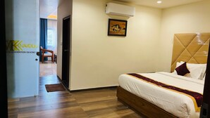 Habitación de hotel con piso de madera, cama con cabecera, aire acondicionado de pared y un cuadro enmarcado.