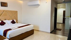 Una habitación de hotel con una cama de madera, ropa de cama blanca y una almohada decorativa roja.