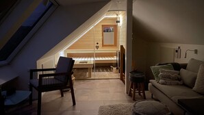 A loft bedroom with a sloped ceiling, a wooden bench, a sofa, and a small table. - Apartment 'Schwarzwald-Wellness byHannes' with Mountain View, Wi-Fi and Air Conditioning (Oberkirch)
