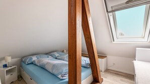 A bedroom with a bed, a nightstand, a window, and a wooden frame.