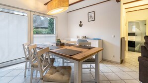 Comedor con mesa de madera, sillas blancas y lámpara colgante.
