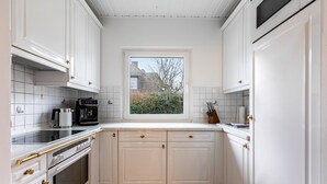 Una cocina con armarios blancos, una ventana y vistas al exterior.