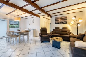 Un vaste espace de vie comprenant une table à manger, des canapés et une lampe moderne.