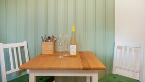 Een houten tafel met een fles wijn, twee glazen en een messenblok.