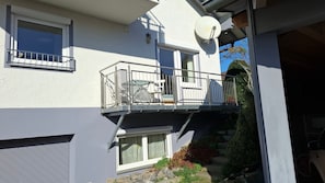 A two-story building with a balcony, satellite dish, and a garage. - Apartment 'Tina' with Balcony and Wi-Fi (Hergensweiler)