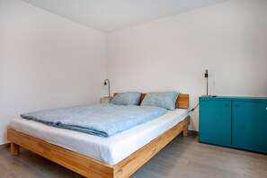 A bedroom with a wooden bed, a teal cabinet, and a white wall. - Apartment 'Tina' with Balcony and Wi-Fi (Hergensweiler)