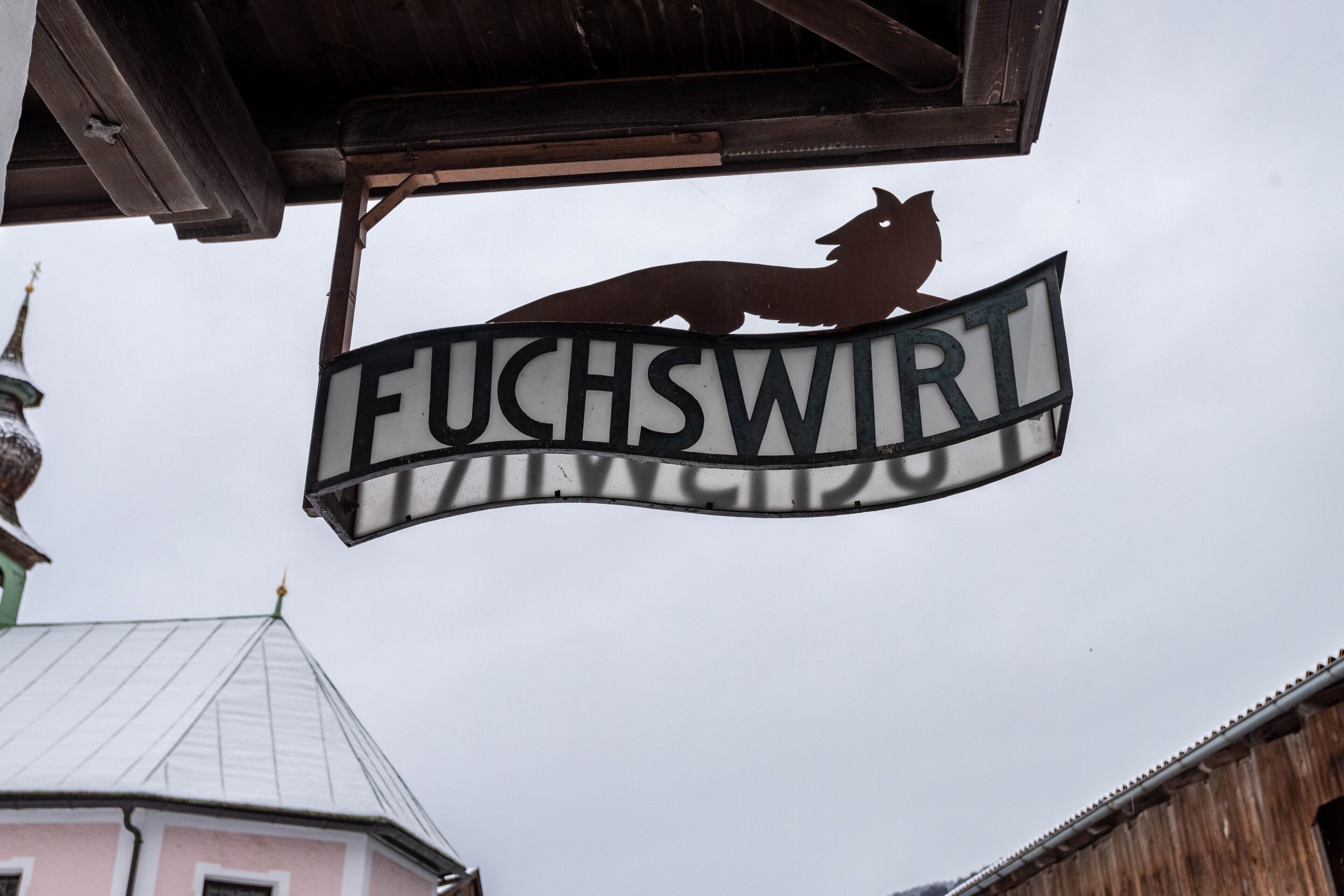 A sign with a wolf silhouette and the word 'FUCHSWIRT' on a building.