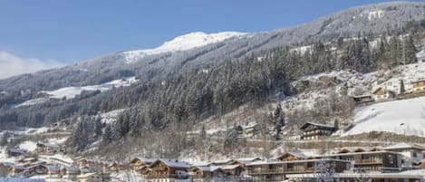 Un pueblo cubierto de nieve en la montaña, con edificios de madera y un cielo azul despejado.