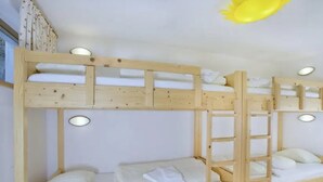 Una cama litera con escalera, ropa de cama blanca y una lámpara en el techo.