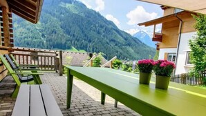 Una terraza con vistas a la montaña, una mesa de madera y un banco.