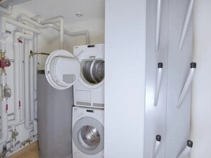 A laundry room with two stacked washing machines and a water heater.