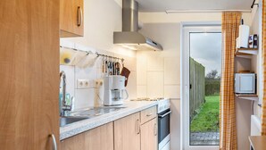 Una cocina moderna con horno empotrado, cafetera y ventana con vista a un jardín.