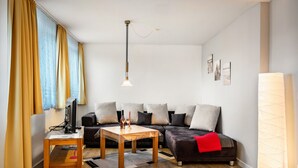 Una sala de estar moderna con un sofá, una mesa de centro, un televisor y una lámpara.