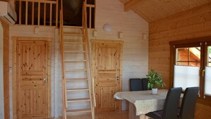 Un intérieur en bois comprenant une table à manger, des chaises, une plante en pot et un escalier en bois.