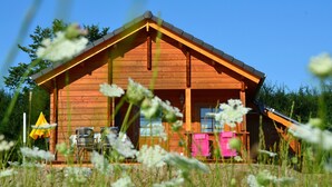 Une cabane en bois avec un toit à deux versants, une véranda avec des chaises et une boîte aux lettres bien visible.