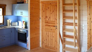 Un intérieur en bois comprenant une cuisine, un escalier et un espace aménagé en mezzanine.