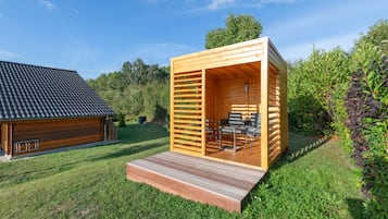 Eine Holzjagdhaus mit einer Terrassenfläche, einem Essplatz und Blick auf die umliegende Natur.