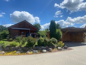 Une cabane en bois avec un porche, un mur en pierre et une allée pavée.