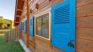 Eine Holzhütte mit blauen Fensterläden und einer kleinen Figur daran.