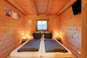 A wooden cabin room with a bed, two bedside tables, and a window. - Holiday Home 'Ferienhaus Gross Nemerow' with Private Terrace, Wi-Fi and Air Conditioning (Groß Nemerow)