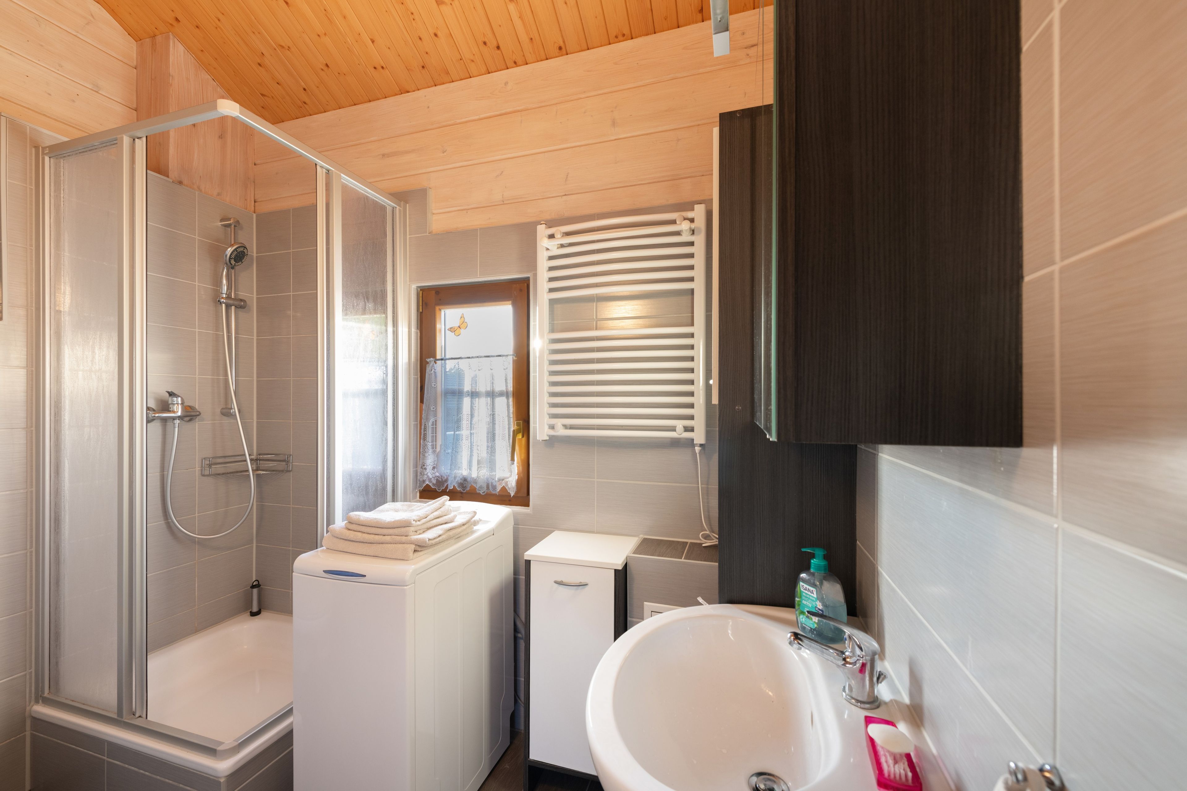 A modern bathroom with a shower, a toilet, a sink, and a window with blinds.