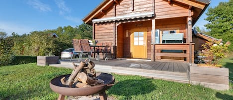 Une cabane en bois dotée d’un patio, d’un foyer et d’une terrasse.