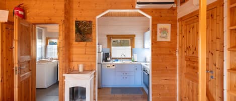 Interior de una cabaña de madera con cocina, chimenea y baño.