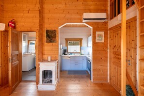 A wooden cabin interior with a kitchen, a fireplace, and a bathroom. - Holiday Home 'Ferienhaus Gross Nemerow' with Private Terrace, Wi-Fi and Air Conditioning (Groß Nemerow)