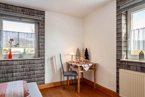 A corner room with a wooden table, a chair, a lamp, and a window with a view. - Apartment 'Möblierte Wohnung Ferienwohnung' with Shared Terrace, Shared Garden and Wi-Fi (Aicha vorm Wald)