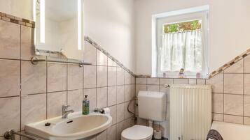 Ein Badezimmer mit Waschbecken, Toilette und Fenster.