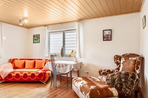Una stanza accogliente con soffitto in legno, un divano, una sedia, un tavolo e una finestra con tende.