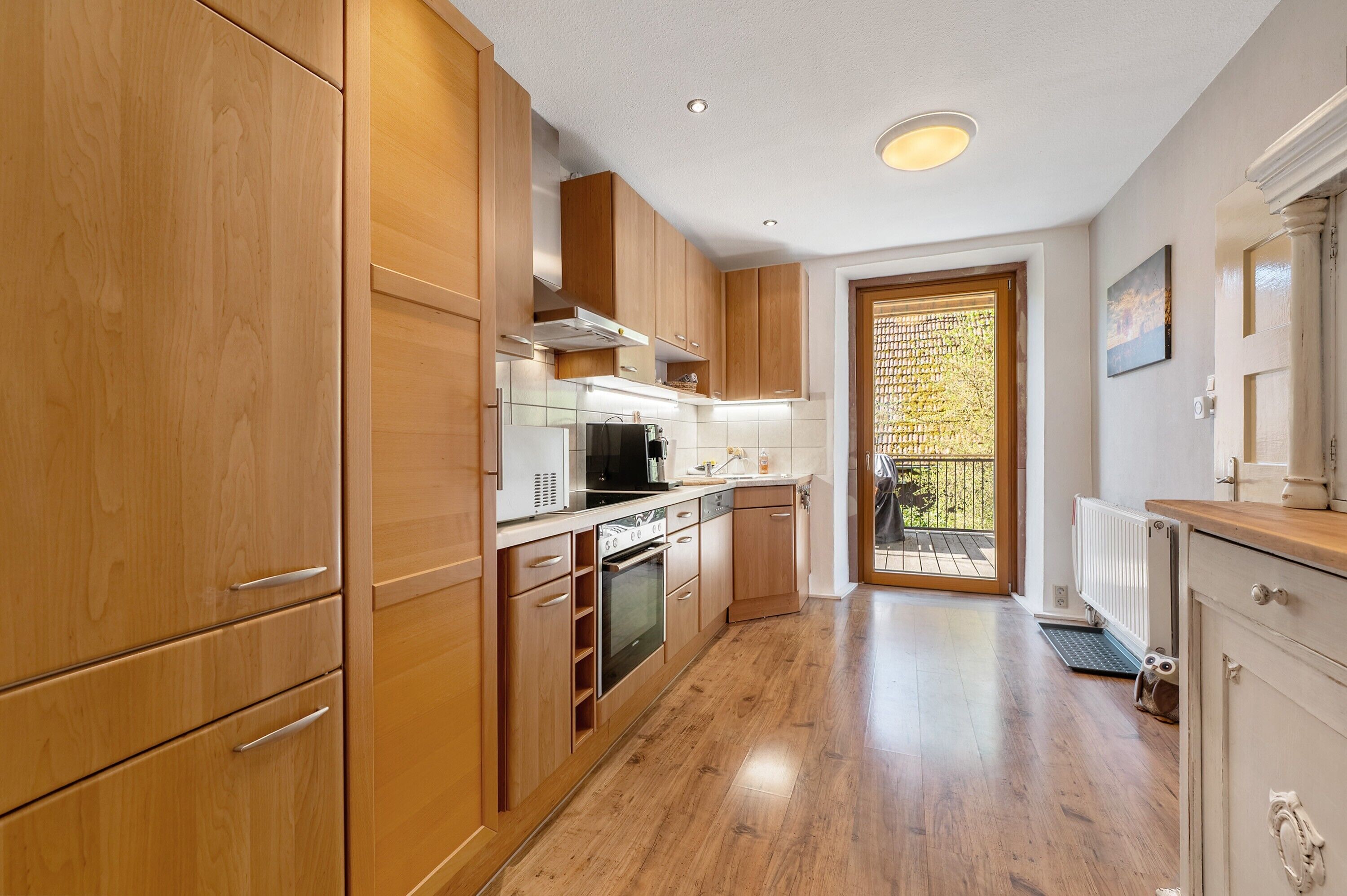 Une cuisine moderne avec des meubles en bois, des appareils électroménagers en acier inoxydable et une vue sur l’extérieur.