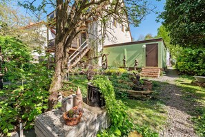 Un giardino con un albero, una piccola rimessa e un edificio con una scala.