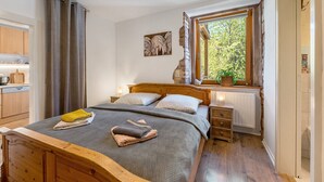 A bedroom with a bed, a window with a view, a radiator, and a wooden headboard.