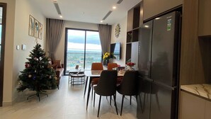 Una cocina moderna con refrigerador empotrado, una zona de comedor con mesa y sillas, y un árbol de Navidad.