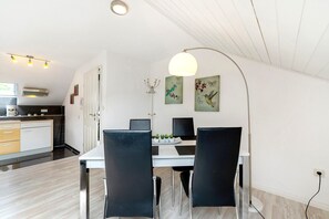 A modern kitchen with a dining area, white walls, and a ceiling with exposed beams. - Apartment '2' with Wi-Fi (Thaleischweiler-Fröschen)
