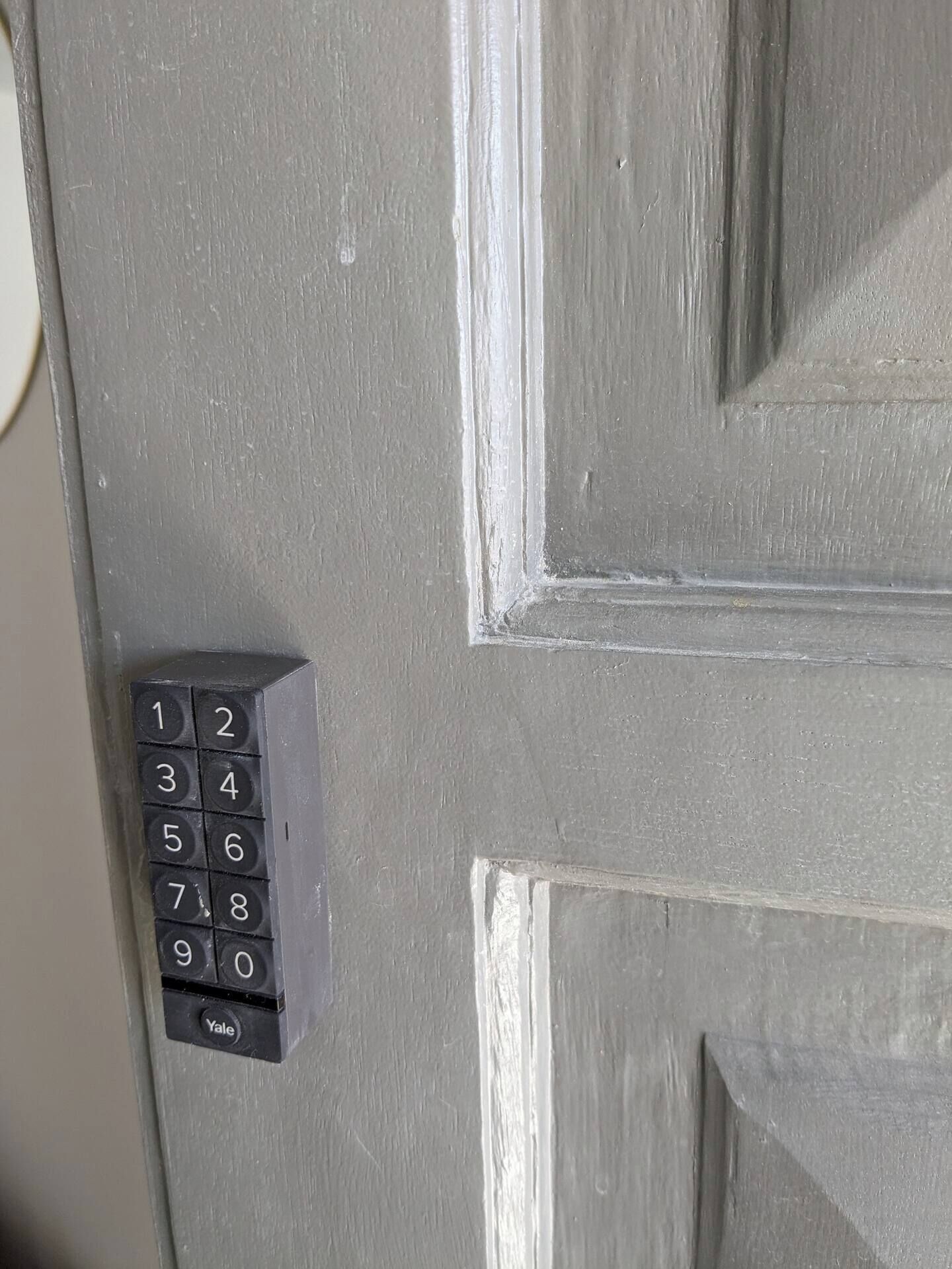 Una puerta gris con teclado numérico y cerradura de la marca Yale.