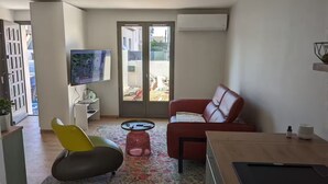 A modern living room with a sofa, a yellow chair, a small coffee table, and a TV. - Petite Bulle, a place of calm and relaxation close to the town center. (Narbonne)