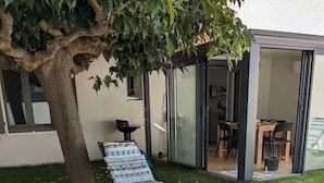 A backyard with a swimming pool, a lounge chair, a tree, and a glass-enclosed patio area. - Petite Bulle, a place of calm and relaxation close to the town center. (Narbonne)